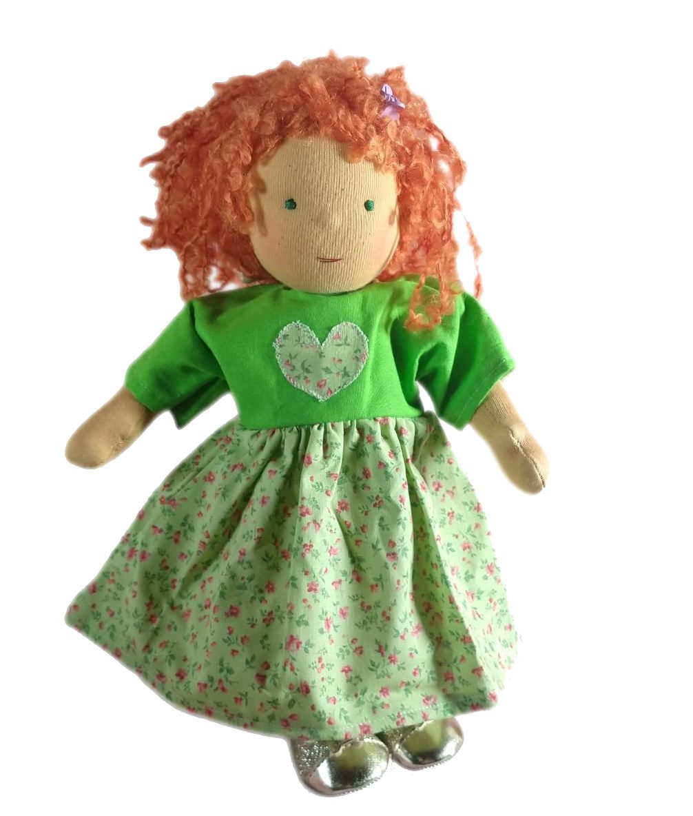 Ronja von Susis Puppenglück Das Foto zeigt ein stehendes Stoffpuppenmädchen mit rotlockigem Haar. Sie trägt ein grünes Kleid mit Herz-Applikation und Streublümchen.