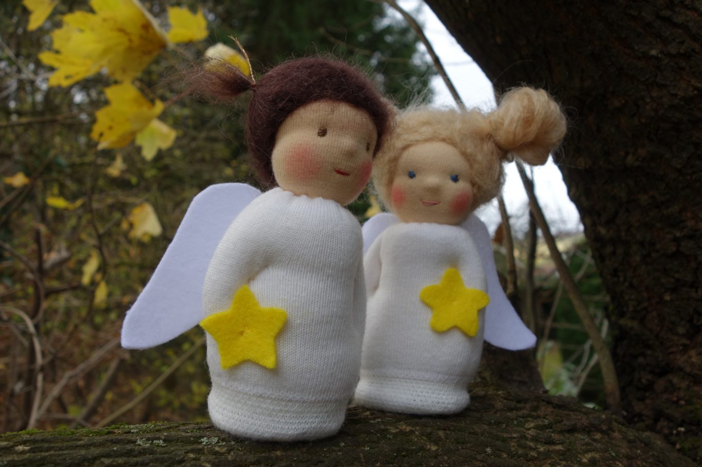 2 Engelpüppchen. Eine blond im Hintergrund und eine mit braunen Haaren im Vordergrund. Schauen sich im herbstlichen Garten um.