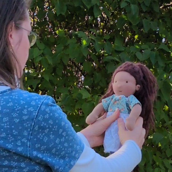 Susanne mit Lilibeth Das Foto zeigt mich von schräg hinten mit Blick auf die Puppe in meinen Händen. Diese ist eine Gliederpuppe mit braunem, langem Haar