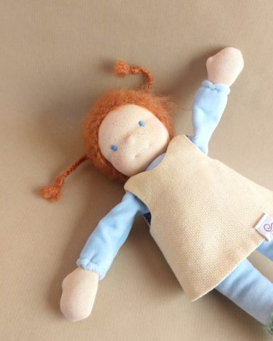 Man sieht eine Schmusepuppe mit hellblauem Nicky-Körper und roten Zöpfen. Sie trägt ein gelbes Kleid und purzelt durchs Bild